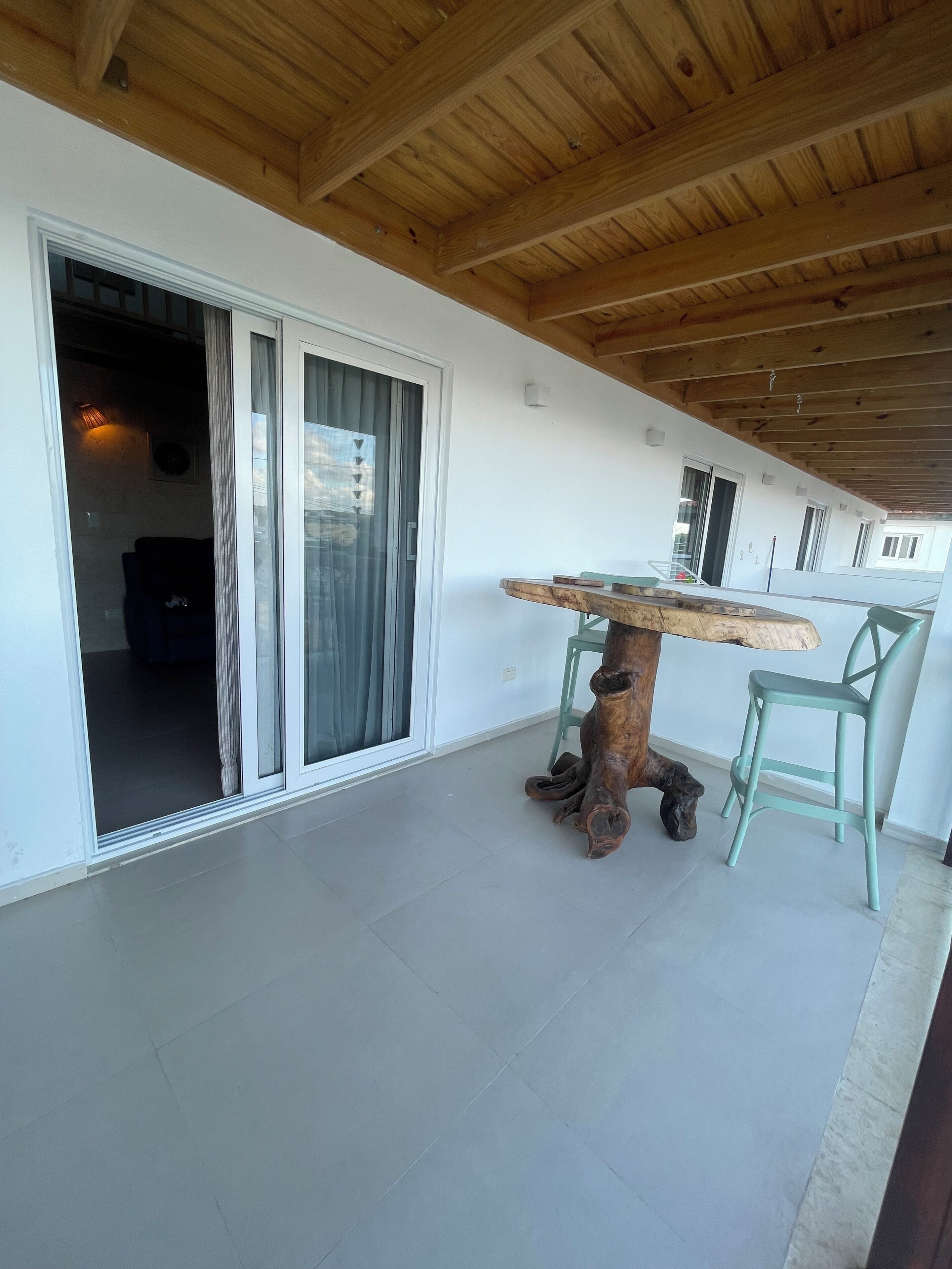 A wooden ceiling, a table with chairs, and a sliding glass door.