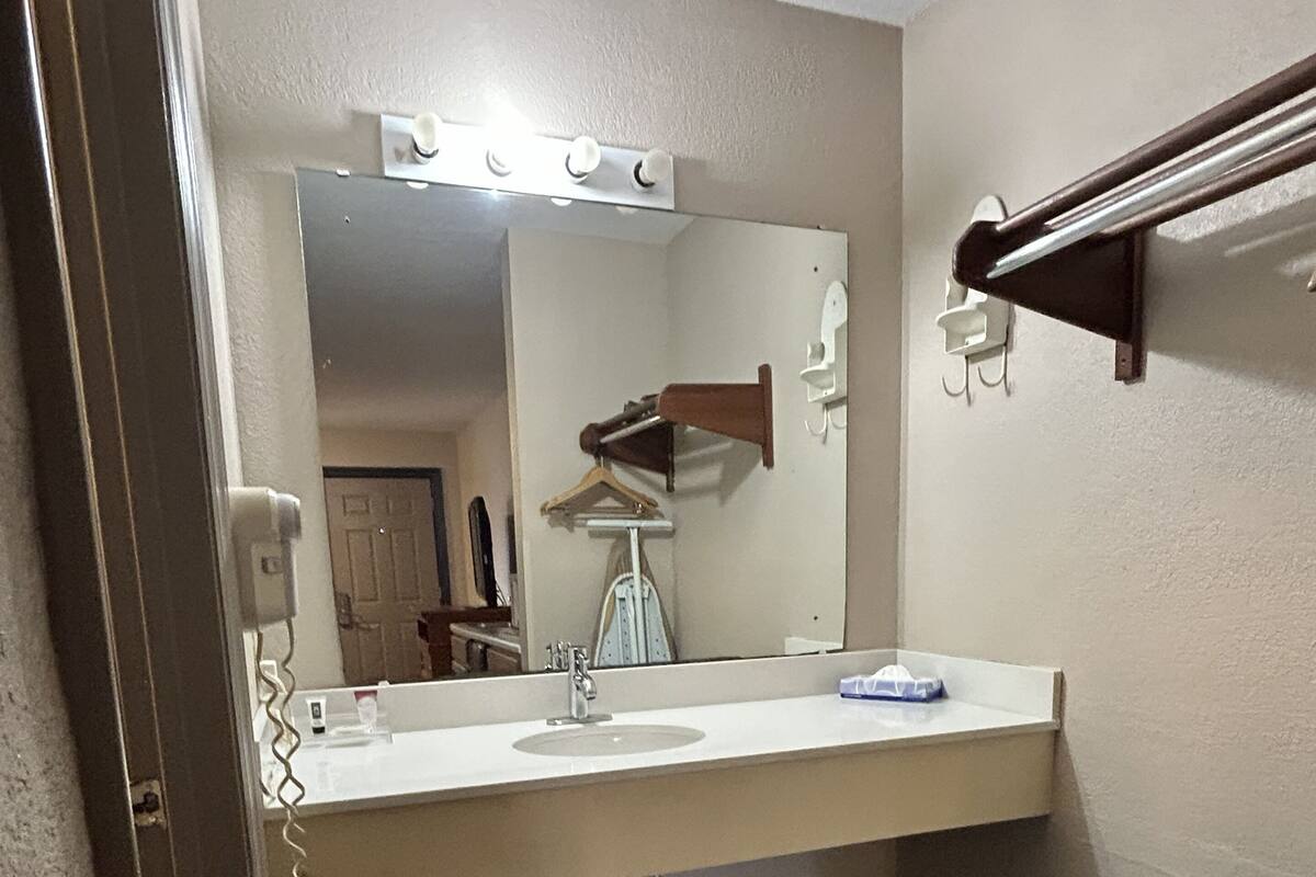 A bathroom with a vanity, mirror, and a towel rack.