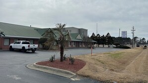 A parking lot with a white pickup truck, a building with a green roof, and a sign for 'Lodge Inn Extended Stay'. - Lodge Inn Extended Stay (Goldsboro)