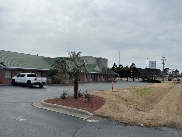 A parking lot with a white pickup truck, a building with a green roof, and a sign for 'Lodge Inn Extended Stay'. - Lodge Inn Extended Stay (Goldsboro)