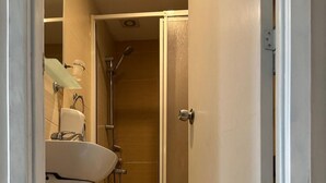 Une petite salle de bain comprenant une douche, des toilettes et un lavabo.