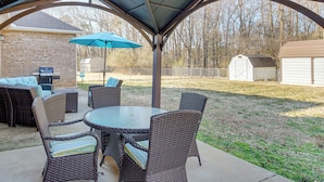 Une terrasse couverte, aménagée avec des meubles en osier et agrémentée d’un parasol bleu.