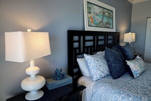 A neatly arranged bedroom with a bed, pillows, a nightstand, a lamp, and a decorative item. - Luxury Fort Myers Beachfront Penthouse - Sunset Views & Pool (Fort Myers Beach)