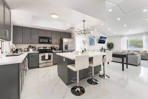 Une cuisine moderne avec des meubles gris, des appareils en acier inoxydable et un îlot central doté de tabourets de bar.