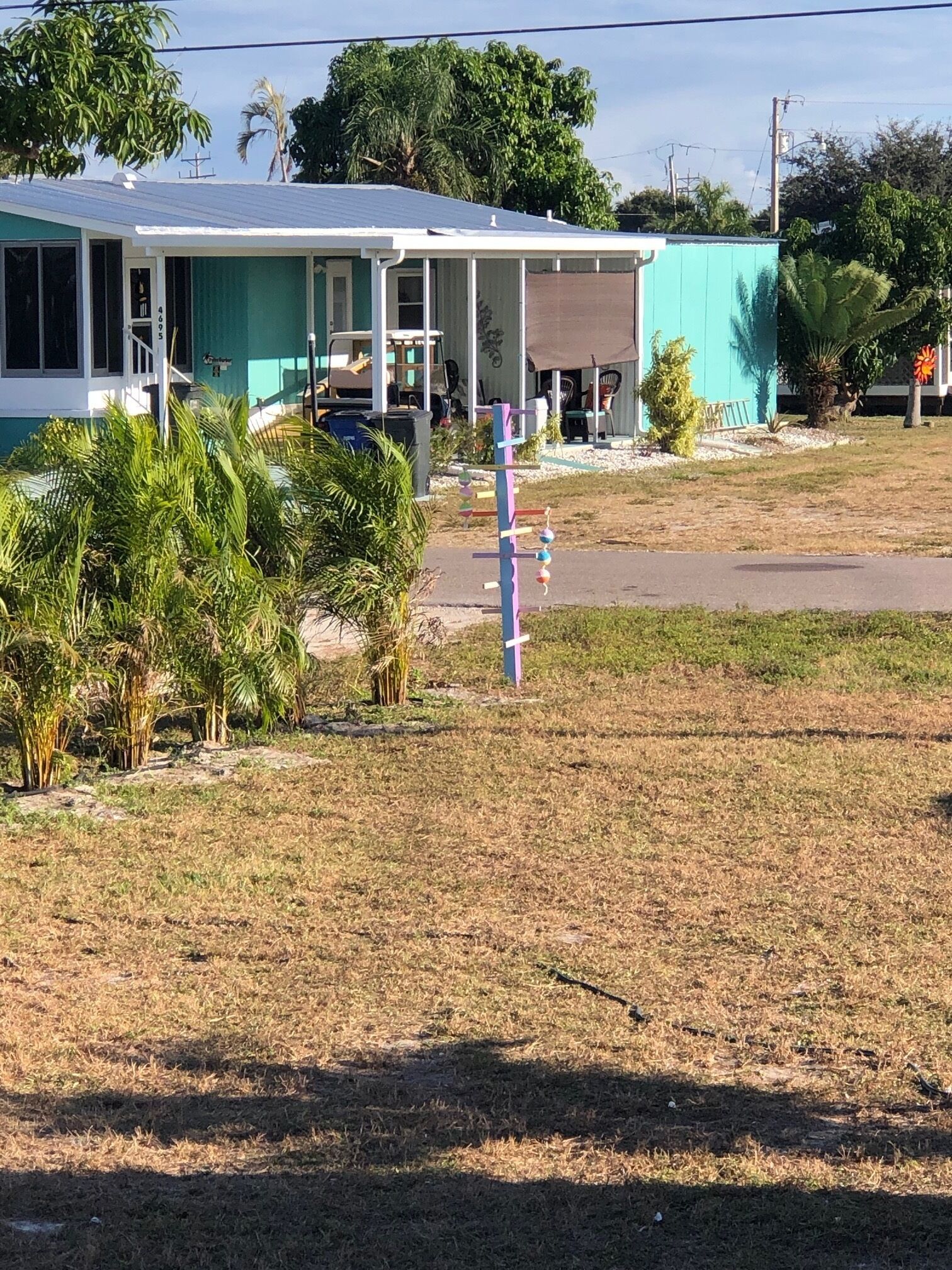 Een huis met een veranda, omringd door droog gras en palmbomen.