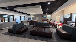 Eine moderne Hotelhalle mit Bar, Sitzbereichen und einem Fernsehbildschirm.