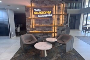 A lobby with a neon sign, two round tables, and four chairs. - Hawthorn Extended Stay by Wyndham Miamisburg Dayton South (Miamisburg)