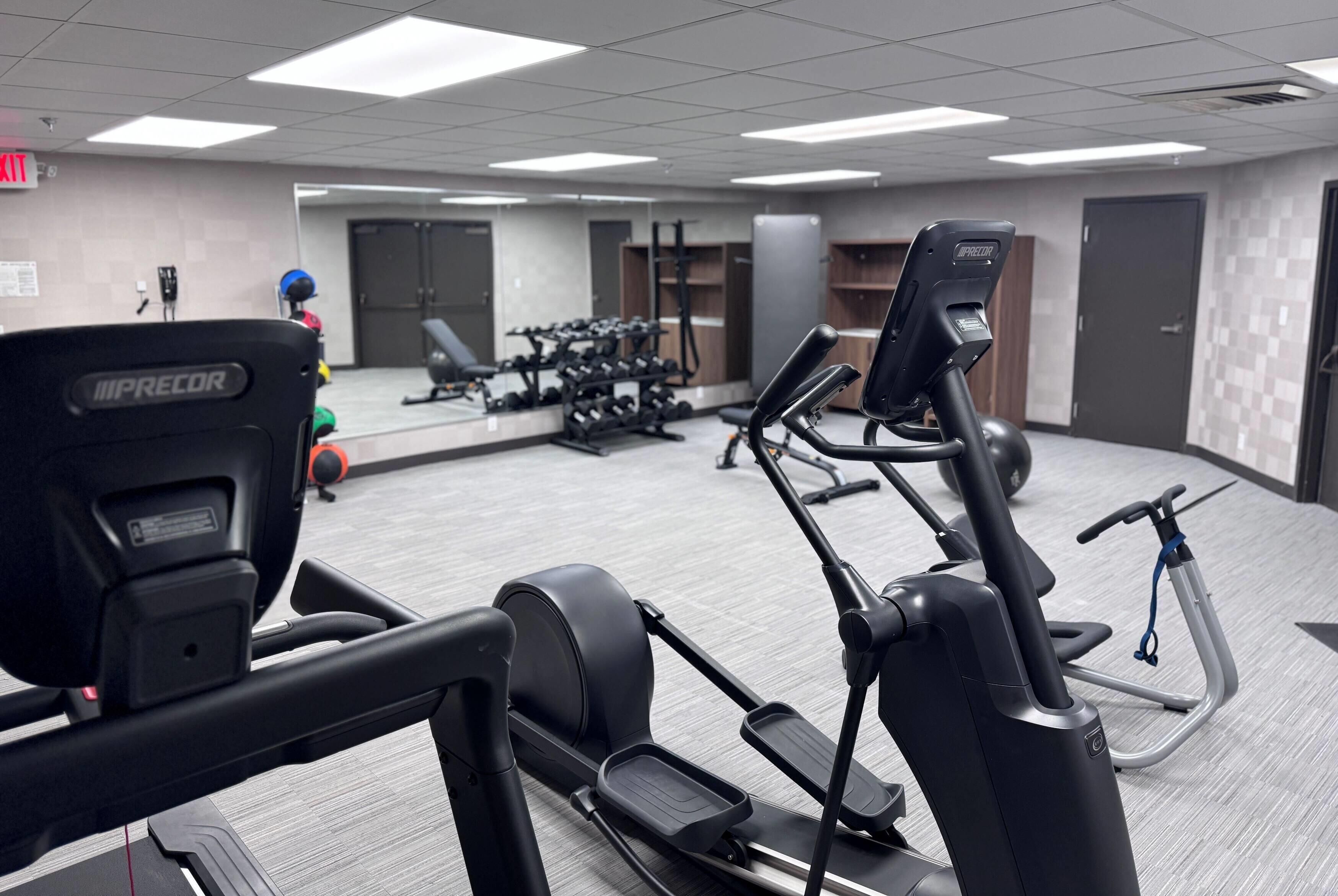 Een sportschool met loopbanden, een hometrainer en krachttoestellen.