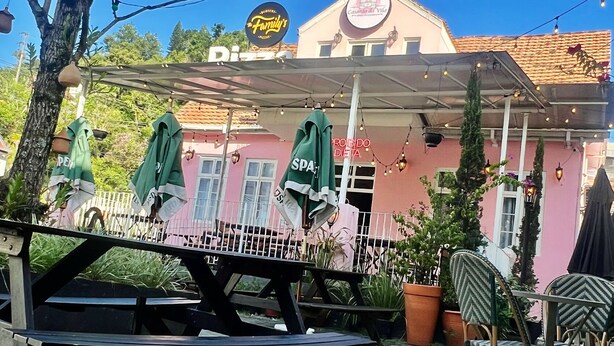 A restaurant with outdoor seating, a covered patio, and a pink building with a sign that reads "Casarinha da Vila." - Casarão da Vila Smart Hospedaria (Blumenau)