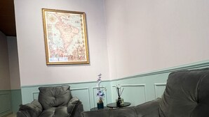 A room with two grey sofas, a framed map on the wall, and a small table with a vase and candle. - Casarão da Vila Smart Hospedaria (Blumenau)