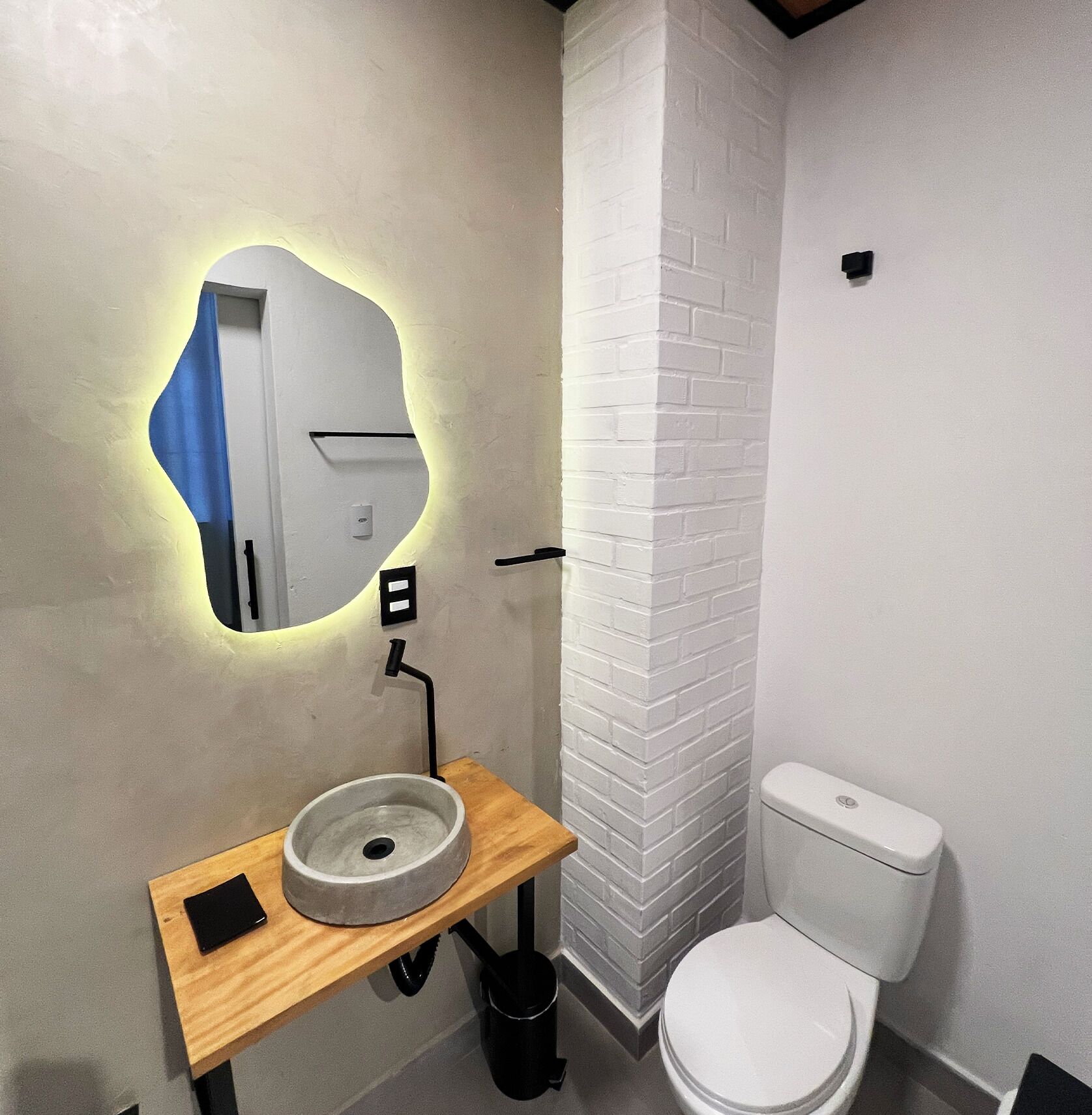 A bathroom with a white toilet, a round sink with a mirror, and a wooden countertop.