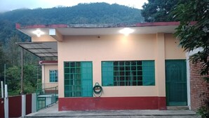 A building with a red and beige facade, green windows, and a green door.