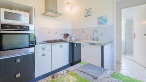 A modern kitchen with a microwave, oven, and gas stove, a sink, and a glass shower enclosure. - La Cupinoise Gite in Ardèche Nature, Terrace & Valley View (Antraigues sur Volane)