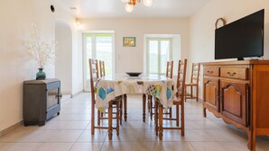 A dining area with a table, chairs, a television, and a fireplace. - La Cupinoise Gite in Ardèche Nature, Terrace & Valley View (Antraigues sur Volane)