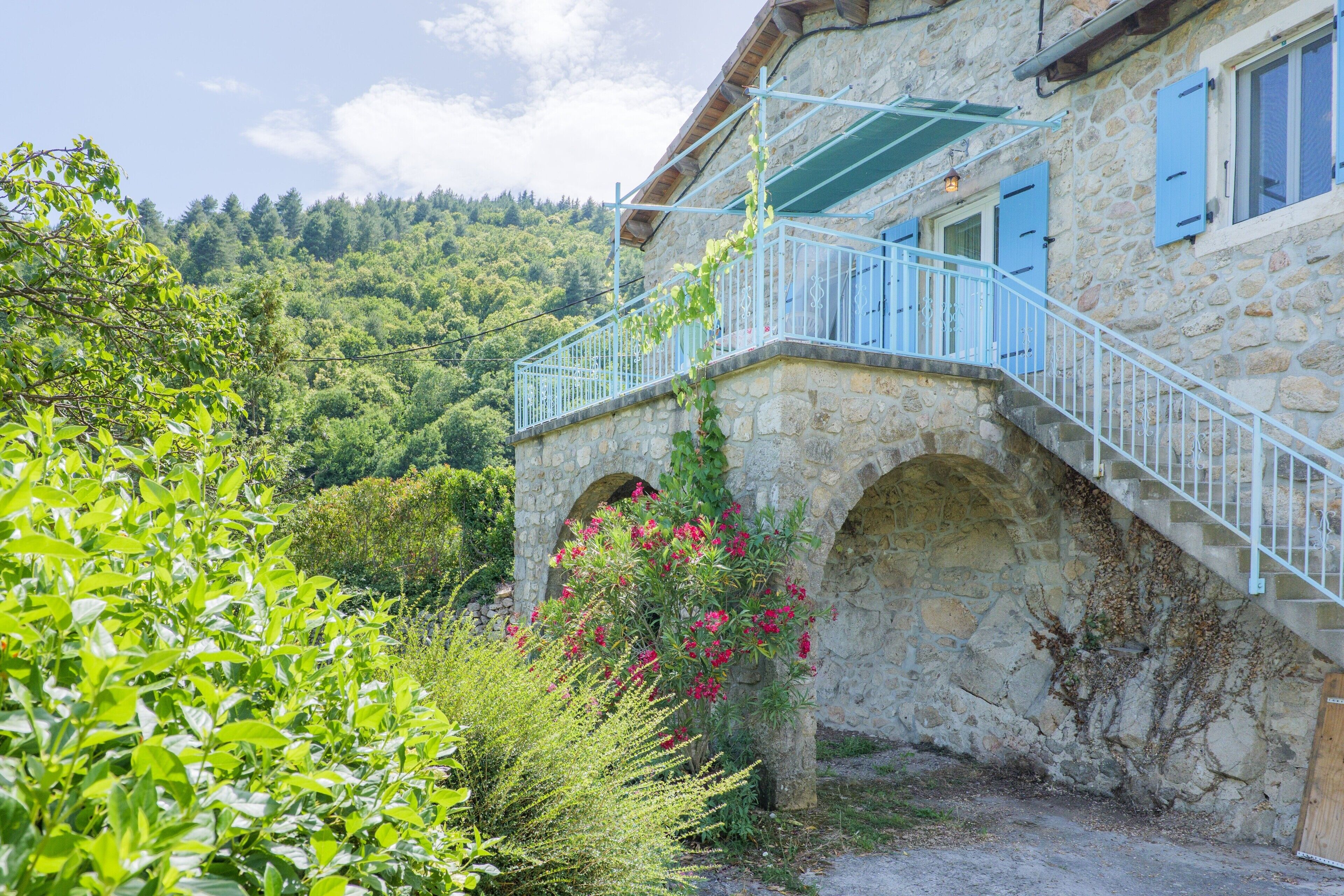 A stone building with a balcony, arched windows, and a staircase leading to the entrance.