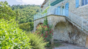 A stone building with a balcony, arched windows, and a staircase leading to the entrance. - La Cupinoise Gite in Ardèche Nature, Terrace & Valley View (Antraigues sur Volane)