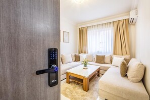 Un saló modern amb un sofà, una taula de centre i una porta amb pany digital.