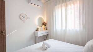A hotel room with a bed, a bedside table with a mirror, a clock, and a window with sheer curtains. - Luxury Apartment in Marrakech (Marrakech)