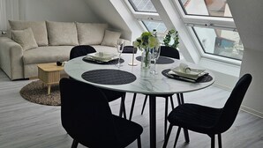 A modern loft bedroom with a skylight, a dining area with a round table, and a sofa. - Lovely home for you 2 (Biberach an der Riß)