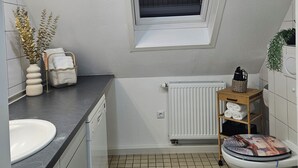A compact bathroom with a window, a radiator, a sink, and a toilet. - Lovely home for you 2 (Biberach an der Riß)