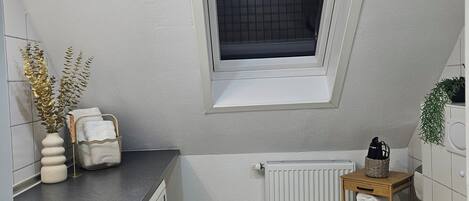 Un baño pequeño con ventana, radiador, lavabo e inodoro.
