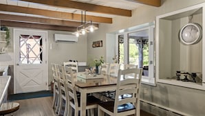 A dining area with a wooden table, white chairs, a hanging light fixture, and a clock on the wall. - Pool | Hot Tub | 3 Min to Lake | Pets Allowed (Auburn)