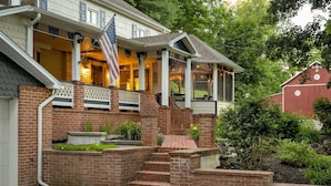 A two-story house with a covered porch, brick steps, and a flag. - Pool | Hot Tub | 3 Min to Lake | Pets Allowed (Auburn)