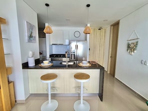 A modern kitchen with two bar stools, a stainless steel refrigerator, and a wooden door. - Great sea views, near beach & historic center (Cartagena de indias)