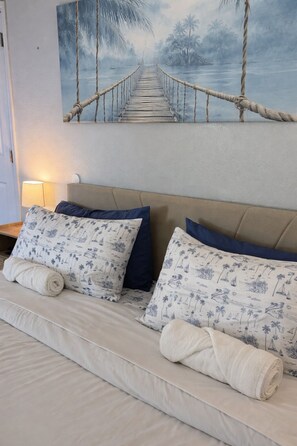 Ein Schlafzimmer mit einem Bett, Kissen und einem Bild einer Seilbrücke über Wasser.