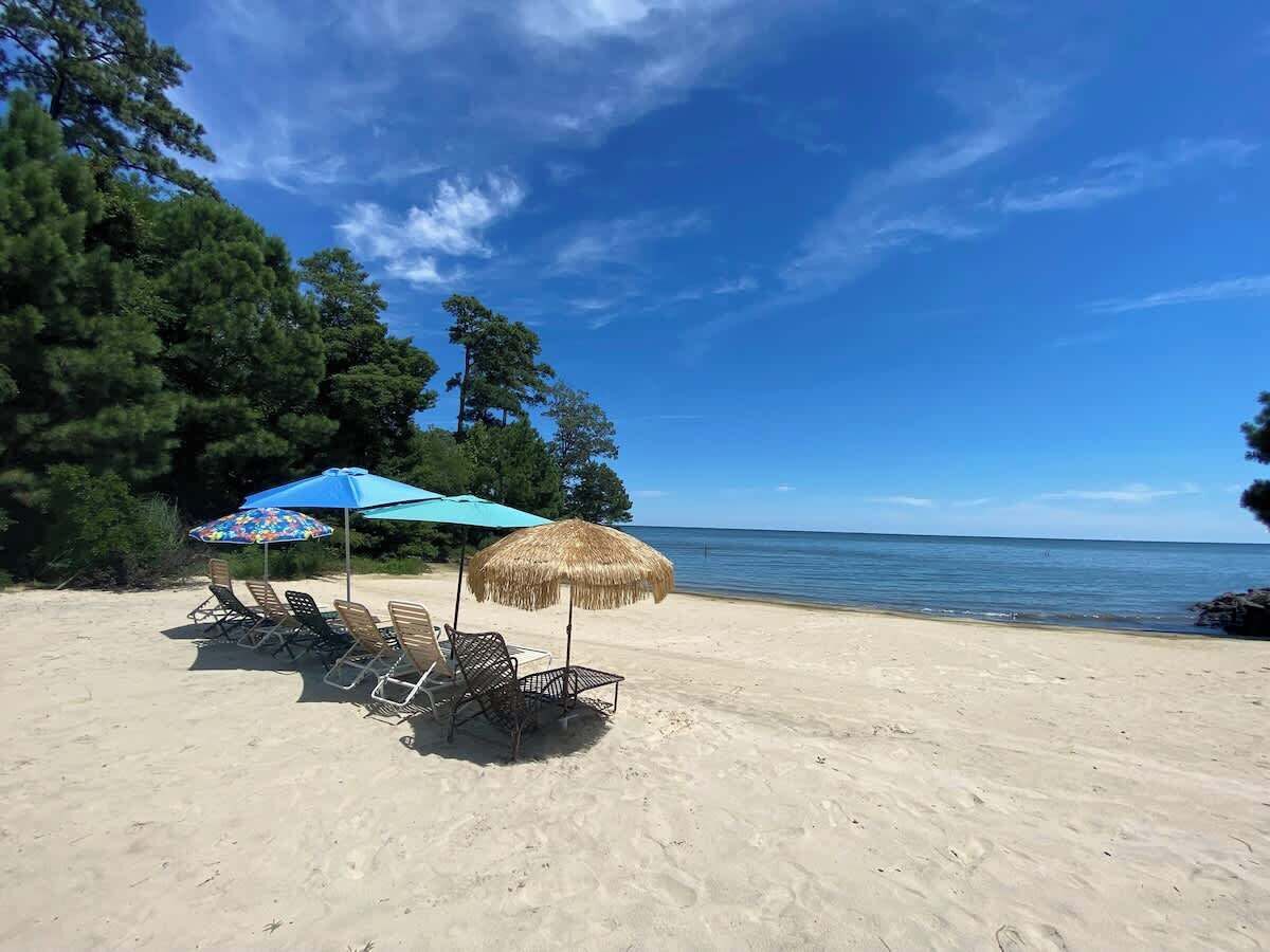 Exclusive beachfront with direct Chesapeake Bay access, featuring outdoor seating and umbrellas—perfect for relaxing, enjoying ocean breezes, and watching stunning sunsets right from the sand.