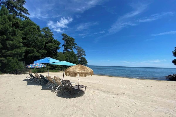 Exclusive beachfront with direct Chesapeake Bay access, featuring outdoor seating and umbrellas—perfect for relaxing, enjoying ocean breezes, and watching stunning sunsets right from the sand.