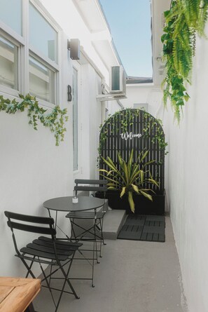 A narrow outdoor space with a table and chairs, a black gate with 'Welcome' sign, and potted plants. - Cozy Miami Suite FREE Parking (Miami)