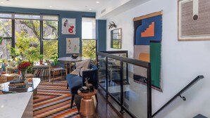A modern living room with a glass coffee table, a blue sofa, and a patterned rug. - Modern Furnished 2BR Bushwick Duplex w/ 2 Private Terraces 1 Block from L Train (Brooklyn)