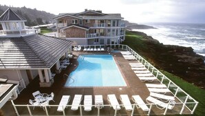 A pool area with lounge chairs and a view of the ocean.