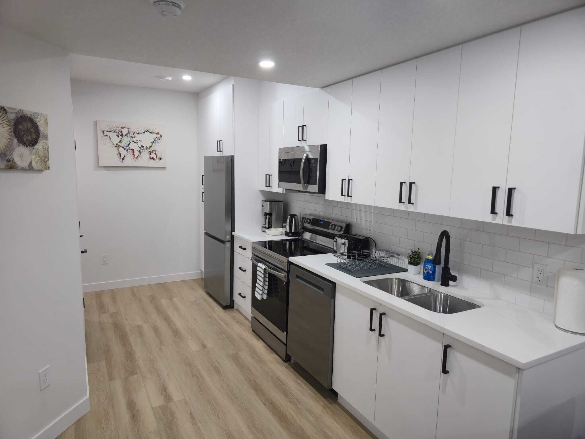 Una cocina moderna con armarios blancos, electrodomésticos de acero inoxidable y suelo de madera.