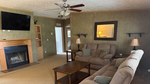 A living room with a fireplace, a sofa, a recliner, a coffee table, a TV, and a ceiling fan. - 3-bedroom private house next to Windrock and Frozen Head State Park (Oliver Springs)
