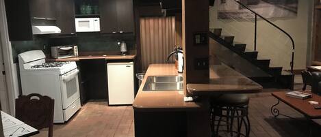 A modern kitchen with a gas stove, microwave, and refrigerator. There is a dining area with a table and chairs.
