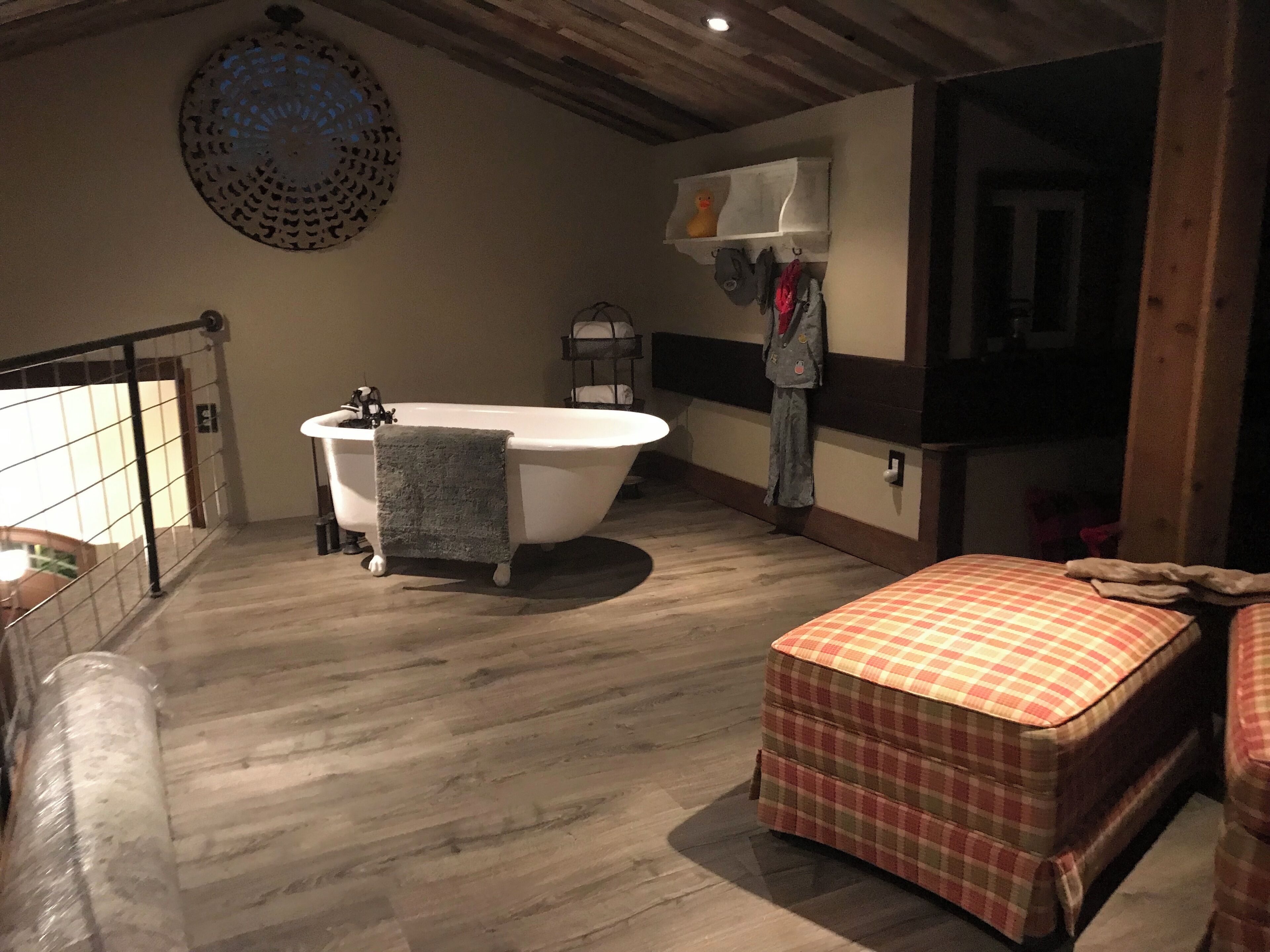 Un baño con una bañera independiente, una toalla colgada y un estante con un patito de goma y bolsas.