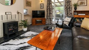 A living room with a fireplace, a television, a sofa, and a coffee table. - Barton Lodge (Minehead)