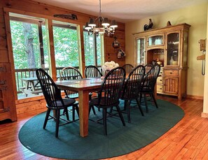 A dining area with a wooden table and chairs, a chandelier, and a wooden cabinet with glass doors. - Campbell Station Beautiful!!! Authentic log cabin! hot tub outdoor fireplace (Gatlinburg)
