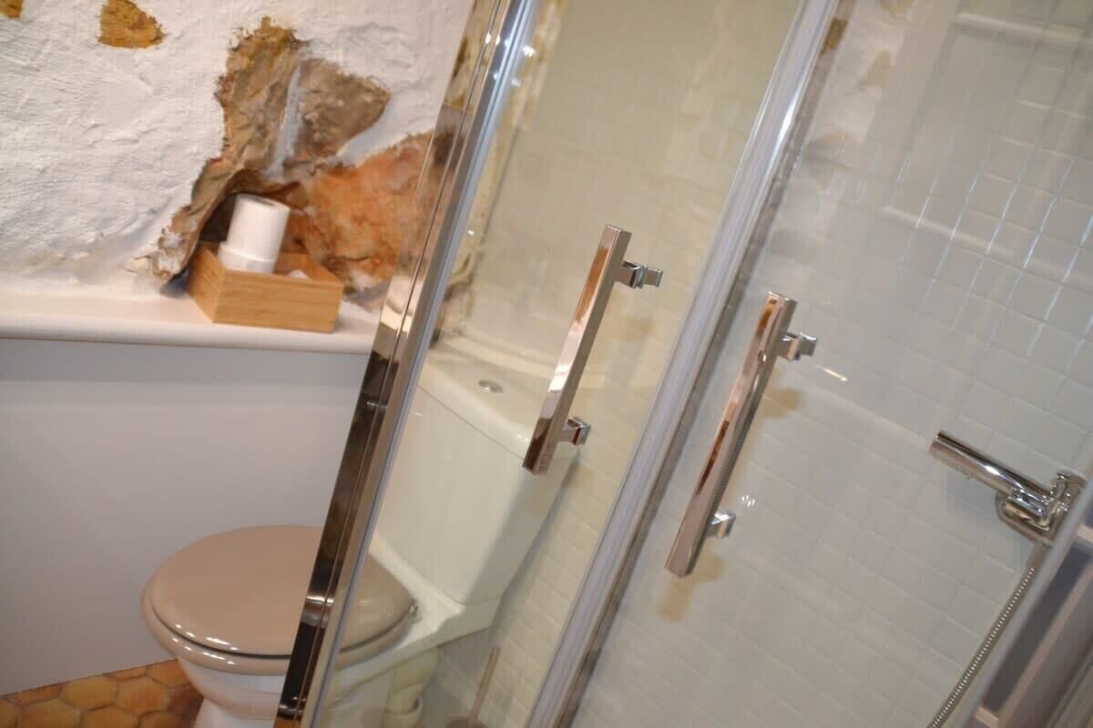 Un baño con inodoro, cabina de ducha y una caja de madera sobre el lavamanos.