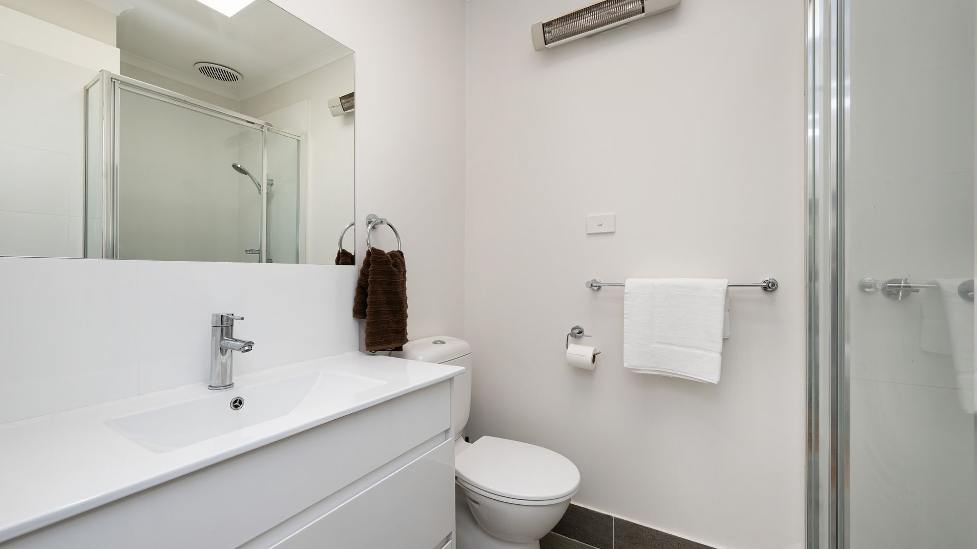 A modern bathroom with a glass shower enclosure, a white sink, and a toilet.