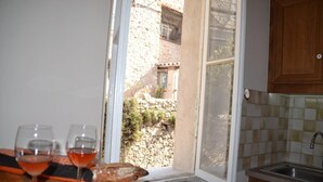 Una cocina con ventana, un lavabo y dos vasos de vino tinto sobre la encimera.