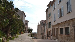 Una calle estrecha flanqueada por edificios con fachadas de piedra y ventanas con contraventanas.