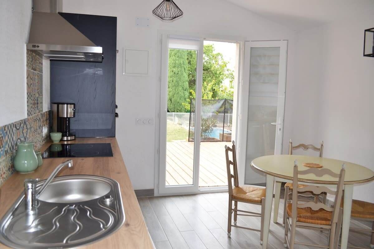 A kitchen with a sink, stove, and a dining area with a table and chairs.