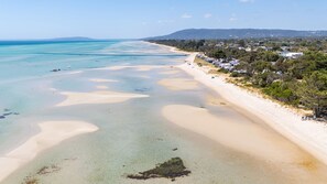 A beach with clear waters and a sandy shore, surrounded by trees and houses. - Pet Friendly - Arcadia by the Beach (Tootgarook)