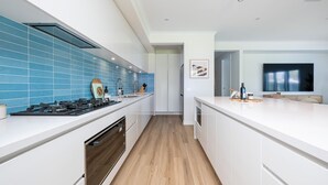 Una cocina moderna con armarios blancos, baldosas azules y suelo de madera.