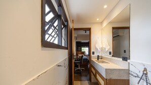 A narrow hallway leading to a bathroom with a large mirror, a sink, and a towel rack. - Casa com Piscina e rea Gourmet em Barra do Una (São Sebastião)