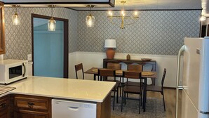 A modern kitchen with a central island, wooden cabinets, a built-in microwave, and a refrigerator.