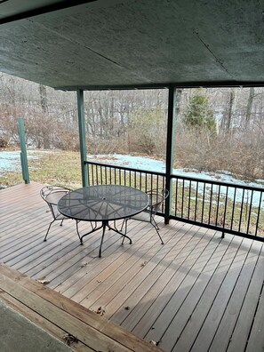A covered outdoor deck with a round metal table and chairs, surrounded by a metal railing. - Newly Renovated 3BR : Quartz Kitchen : Fast Fiber WiFi : Carport Parking (Campbell)